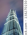 仰望天空，可以看到一座幾何形狀的玻璃摩天大樓呈階梯狀拔地而起，映襯著陰沉的紫色天空。 138270150