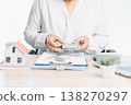 Real estate financing and mortgage payment concept with consultant counting US dollar bills above a clipboard, calculator and house model, symbolizing down payment, loan approval and budgeting. 138270297