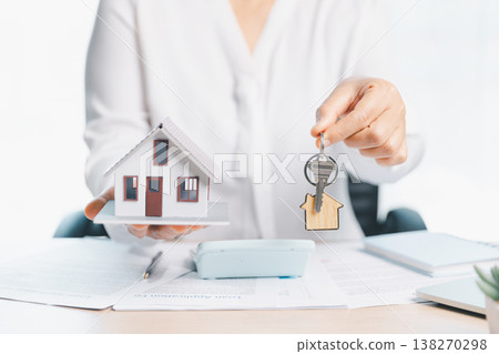 Home purchase and rental agreement concept with agent handing over house keys and keychain above contract clipboard, miniature house model, calculator, laptop on bright office desk. rental agreement Home purchase and rental agreement concept with agent handing over house keys and keychain above contract clipboard, miniature house model, calculator, laptop on bright office desk. rental agreement 138270298