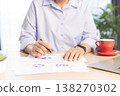 Business professional working on laptop at modern office desk with documents, smartphone and stationery, bright daylight by window. Concept of productivity, remote work and digital management. 138270302