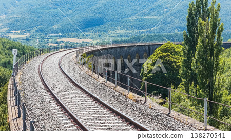 Curving railway viaduct crossing a mountain valley Curving railway viaduct crossing a mountain valley 138270541