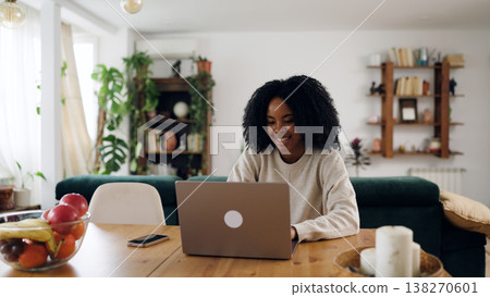 Young woman smiling while working from home on laptop 138270601