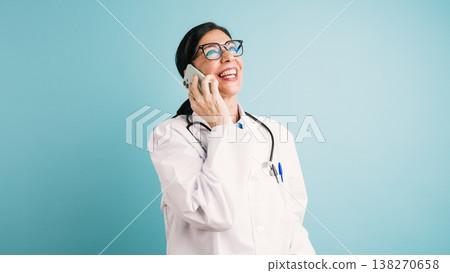 Smiling female doctor talking on a smartphone 138270658
