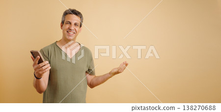 Man smiling holding phone presenting empty space Man smiling holding phone presenting empty space 138270688