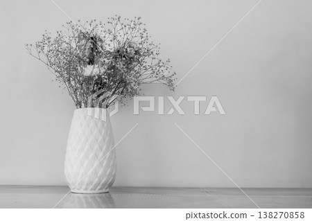 Dead bouquet of flowers sitting in a vase on the table, black and white photo. 138270858