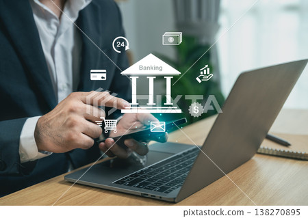 Businessman using smartphone to perform online banking transactions with laptop, financial icons, virtual banking concept, and digital accessibility in modern office 138270895