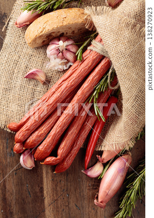 Kabanos with onion, garlic, pepper, and rosemary on an old wooden table. Kabanos with onion, garlic, pepper, and rosemary on an old wooden table. 138270923