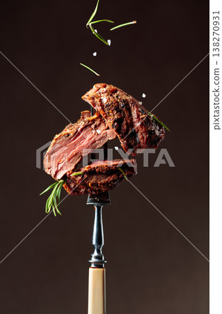 Grilled ribeye beef steak with rosemary on a brown background. Grilled ribeye beef steak with rosemary on a brown background. 138270931