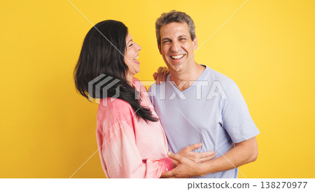 Happy couple embracing laughing on yellow background 138270977