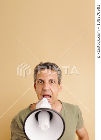 Mature man shouting message through megaphone Mature man shouting message through megaphone 138270983