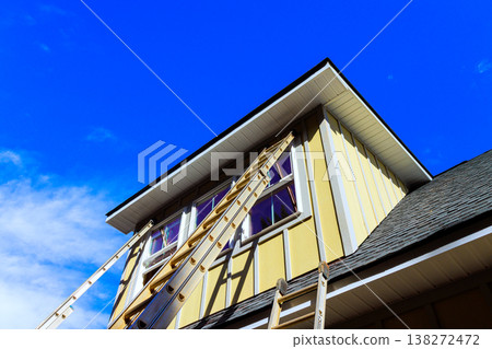 Workers are using ladders to reach upper part of house to carry out maintenance during installing hardie siding panels Workers are using ladders to reach upper part of house to carry out maintenance during installing hardie siding panels 138272472
