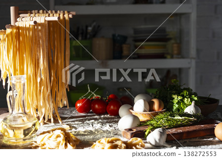 Homemade noodles hanging on wooden dryer rack over messy kitchen table background low angle front view Homemade noodles hanging on wooden dryer rack over messy kitchen table background low angle front view 138272553