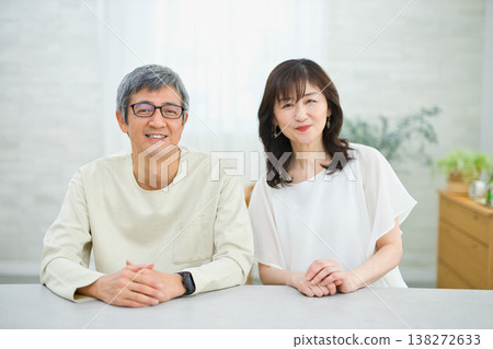 一對六十多歲的夫婦在客廳裡愉快地交談著 一對六十多歲的夫婦在客廳裡愉快地交談著 138272633
