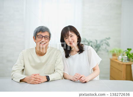 一對六十多歲的夫婦在客廳裡愉快地交談著 一對六十多歲的夫婦在客廳裡愉快地交談著 138272636