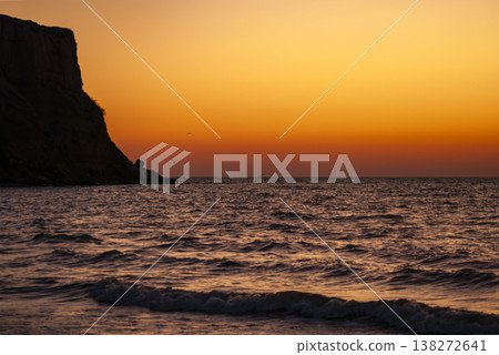 Golden Sunset over the Sea with a Coastal Cliff Silhouette in Ukrainian Crimea Golden Sunset over the Sea with a Coastal Cliff Silhouette in Ukrainian Crimea 138272641