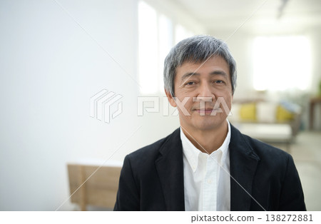 A man in his 60s wearing a jacket and smiling in his room. A man in his 60s wearing a jacket and smiling in his room. 138272881
