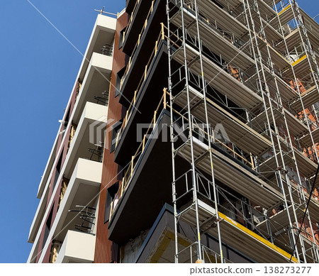 High building under construction with scaffolding and crane against blue sky. Urban development, architecture progress, engineering process, infrastructure growth, city expansion, modern industry High building under construction with scaffolding and crane against blue sky. Urban development, architecture progress, engineering process, infrastructure growth, city expansion, modern industry 138273277