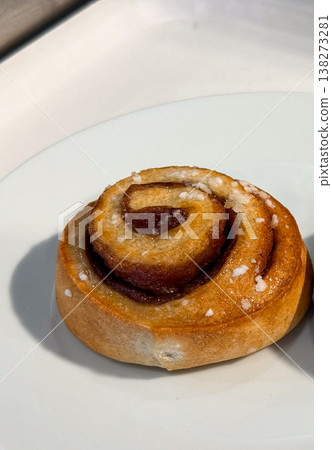 Sweet pastry roll with sugar topping on white plate isolated composition. Dessert indulgence, bakery tradition, comfort food, simple pleasure, homemade style, minimal presentation Sweet pastry roll with sugar topping on white plate isolated composition. Dessert indulgence, bakery tradition, comfort food, simple pleasure, homemade style, minimal presentation 138273281