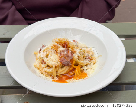 Plate of creamy spaghetti with crispy guanciale grated cheese and egg yolk sauce in white bowl. Italian cuisine, restaurant serving, comfort dining, pasta texture, rich savory meal presentation 138274353