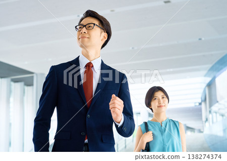 Confident businessmen and businesswomen walk through an office building, their eyes fixed on a bright future. Confident businessmen and businesswomen walk through an office building, their eyes fixed on a bright future. 138274374