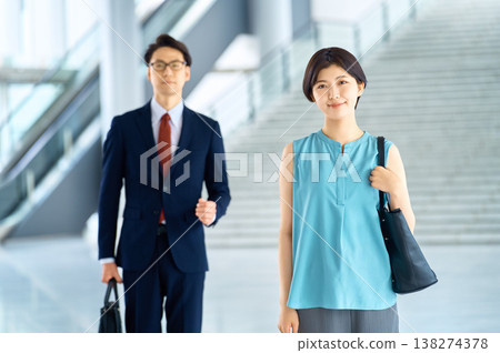 微笑的日本商務人士走過城市的一棟辦公大樓。 微笑的日本商務人士走過城市的一棟辦公大樓。 138274378