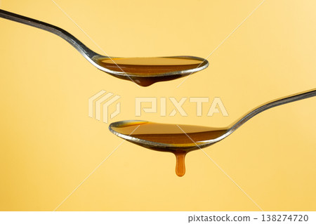 Two spoons with dripping caramel sauce in motion. Two spoons with dripping caramel sauce in motion. 138274720