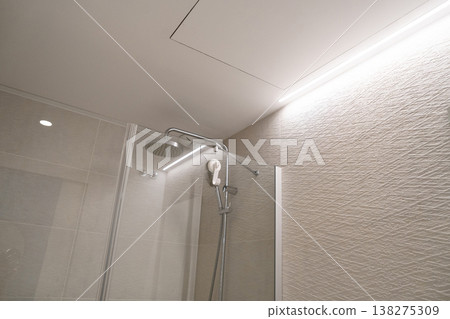 Stainless steel shower head with handheld hose inside a modern bathroom shower cabin featuring glass partition. Minimalist design. Elegant textured wall tiles. Relaxing ambience Stainless steel shower head with handheld hose inside a modern bathroom shower cabin featuring glass partition. Minimalist design. Elegant textured wall tiles. Relaxing ambience 138275309