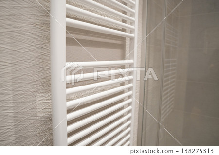 White heated towel rail furnishing a modern bathroom interior, providing warmth and a practical solution for drying towels and enhancing everyday home comfort White heated towel rail furnishing a modern bathroom interior, providing warmth and a practical solution for drying towels and enhancing everyday home comfort 138275313