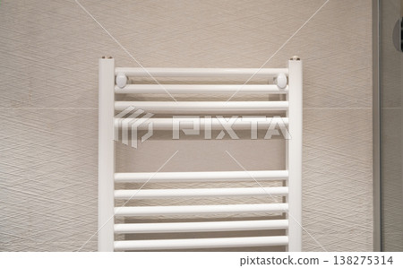 White heated towel rail radiator providing warmth and comfort in a modern home bathroom, featuring contemporary design and sleek wall-mounted heating for interior styling White heated towel rail radiator providing warmth and comfort in a modern home bathroom, featuring contemporary design and sleek wall-mounted heating for interior styling 138275314