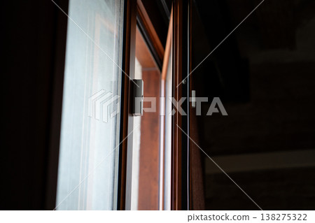 Magnetic contact sensor mounted on a wooden window frame, representing enhanced security, smart home technology, and an advanced electronic alarm system for property protection Magnetic contact sensor mounted on a wooden window frame, representing enhanced security, smart home technology, and an advanced electronic alarm system for property protection 138275322