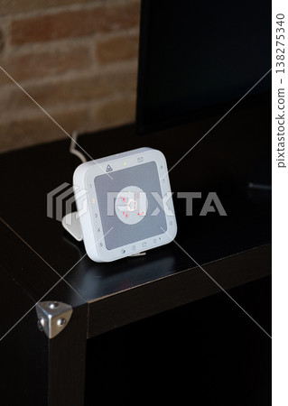 Telecare medical alert system with a glowing red button on a dark table, providing home safety and peace of mind for seniors and independent living at home 138275340