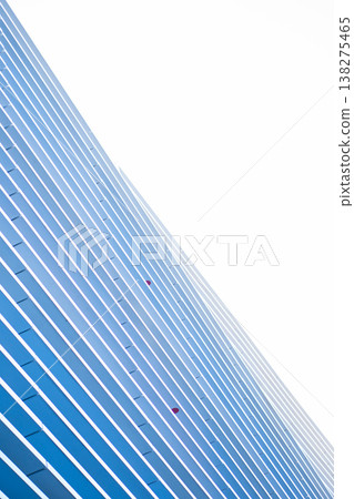 Modern skyscraper facade with parallel blue lines and white structural elements forming an abstract geometric pattern of glass reflections against a bright expansive sky, minimalist Modern skyscraper facade with parallel blue lines and white structural elements forming an abstract geometric pattern of glass reflections against a bright expansive sky, minimalist 138275465