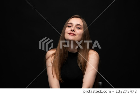 Young woman with long brown hair smiling on black background, presenting beauty, confidence, and lifestyle 138275478