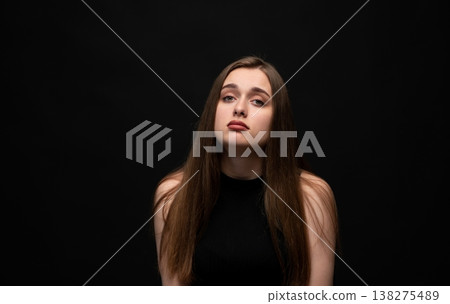 Young woman expressing sorrow and sadness, portraying feelings of loneliness, depression, and grief on a dark background Young woman expressing sorrow and sadness, portraying feelings of loneliness, depression, and grief on a dark background 138275489