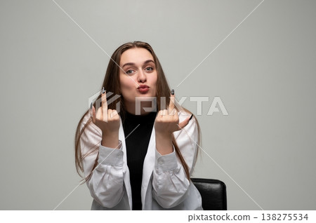 Woman showing rude middle finger gesture, expressing defiance and rebellion with a pouty face 138275534