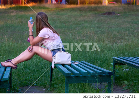 Lonely sad young woman waiting on bench in summer park Lonely sad young woman waiting on bench in summer park 138275731