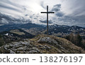 Summit cross on a rugged rocky peak under dramatic cloudy skies  138276197