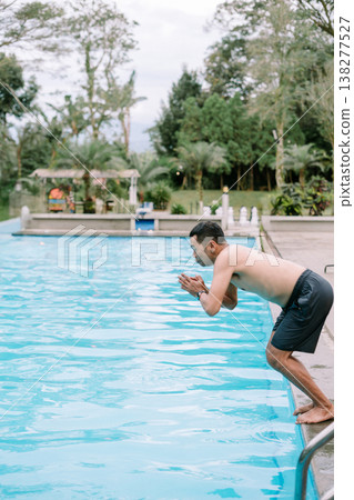 Southeast Asian man about to jump into pool Southeast Asian man about to jump into pool 138277527