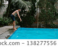 Man jumping into pool in serene outdoor location 138277556