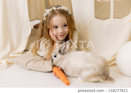 Cute child girl with bunny and carrot in cozy home setup, Easter atmosphere and holiday lifestyle Cute child girl with bunny and carrot in cozy home setup, Easter atmosphere and holiday lifestyle 138277621