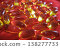 Soft focus fish oil capsules on red background. Omega 3 supplements and wellness concept with glowing translucent softgel pills. 138277733