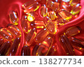 Golden fish oil capsules on red satin fabric with soft folds. Omega 3 supplements concept, health, wellness and nutrition background. 138277734