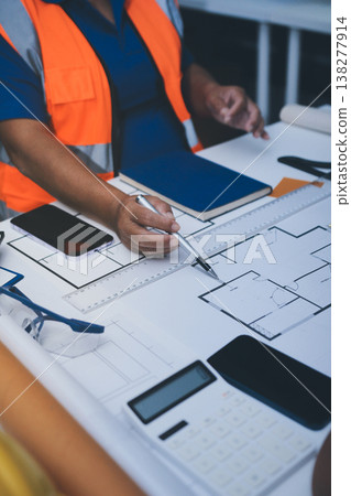 engineer and an architect reviewing blueprints and construction plans together at a bustling construction site engineer and an architect reviewing blueprints and construction plans together at a bustling construction site 138277914