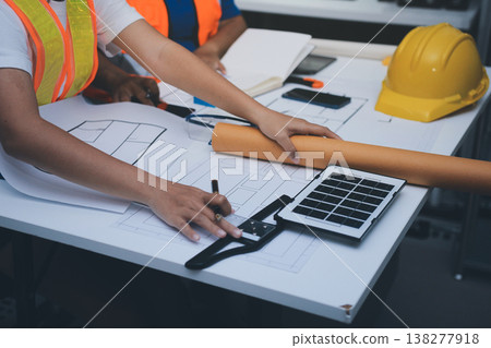 engineer and an architect reviewing blueprints and construction plans together at a bustling construction site 138277918