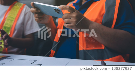 engineer and an architect reviewing blueprints and construction plans together at a bustling construction site engineer and an architect reviewing blueprints and construction plans together at a bustling construction site 138277927