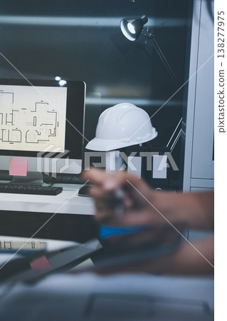 engineer and an architect reviewing blueprints and construction plans together at a bustling construction site 138277975