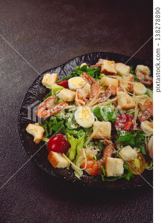 caesar salad with tiger prawns, shrimp salad, lettuce leaves, quail eggs, cherry tomatoes, parmesan cheese, on a black plate, 138278890