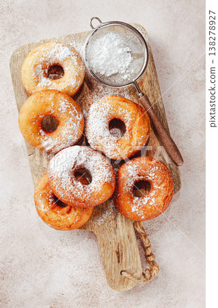 Freshly made doughnuts with powdered sugar, on a wooden board, close-up, home cooking, 138278927