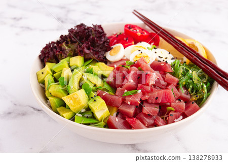Fresh poke bowl, with tuna, avocado, and vegetables, served on a white plate Fresh poke bowl, with tuna, avocado, and vegetables, served on a white plate 138278933