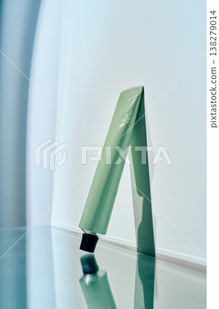 Green cosmetic tube reflecting on shiny surface Green cosmetic tube reflecting on shiny surface 138279014